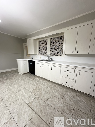 A kitchen with white cabinets and a patterned backsplash.