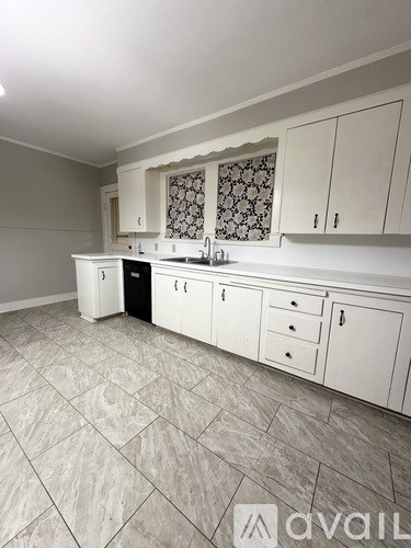 A kitchen with white cabinets and a patterned backsplash.