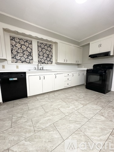 A kitchen with black appliances and white cabinets.