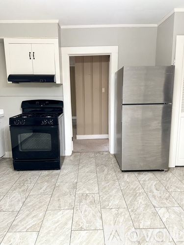 A black stove and a silver refrigerator in a kitchen.