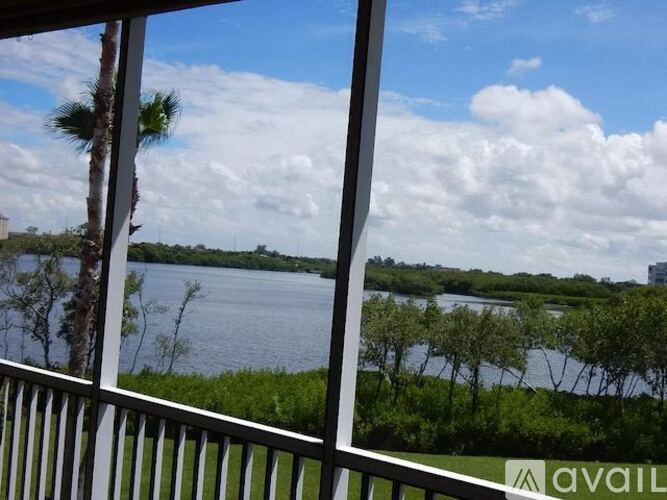 A view from a balcony looking out at a body of water with trees and buildings in the distance.