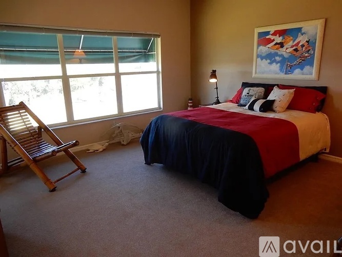 A bedroom with a bed, a chair, and a window.