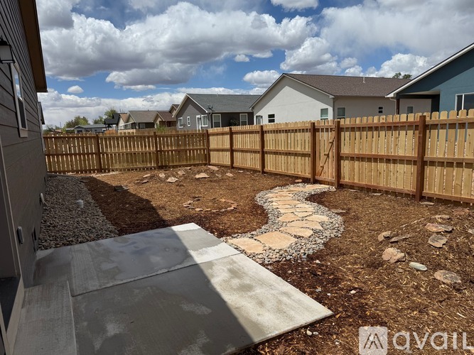A backyard with a wooden fence and a stone pathway.