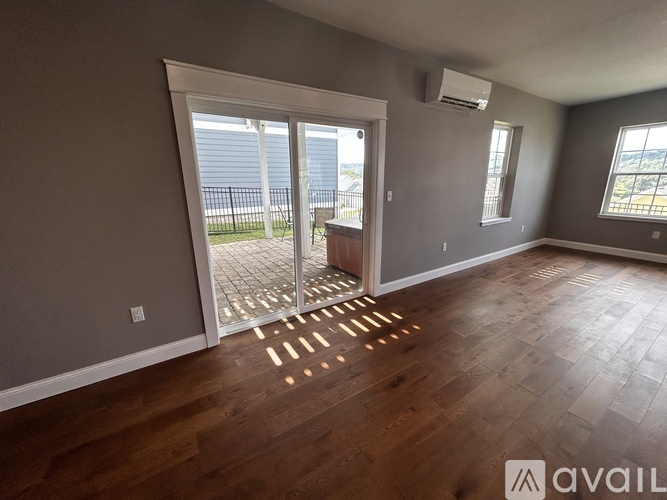 A room with wooden flooring and a sliding glass door leading to a balcony.