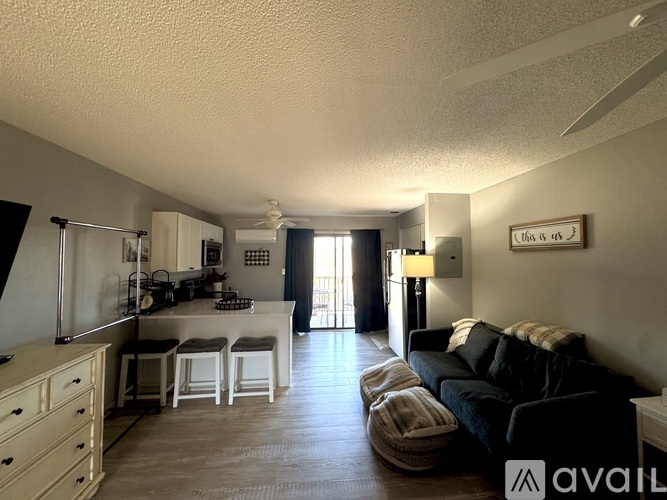 A living room with a couch, a table, and a kitchen area in the background.