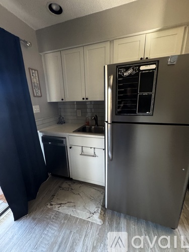 A kitchen with a refrigerator, sink, and cabinets.