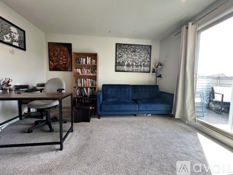 A living room with a blue couch and a desk with a computer.