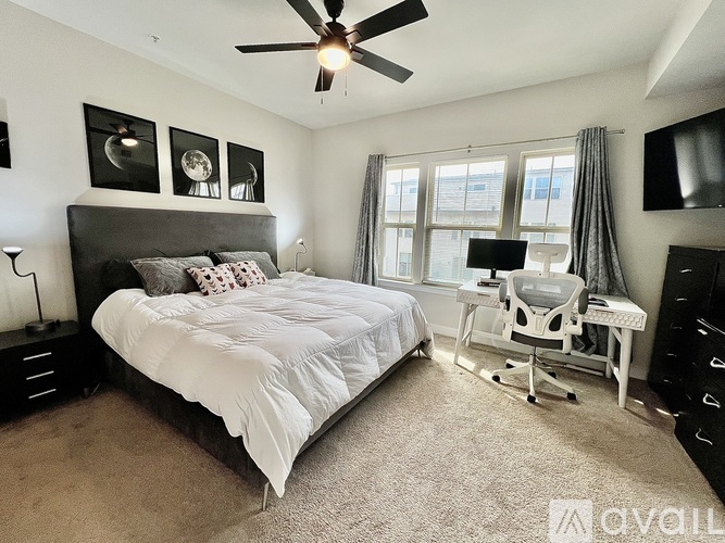A bedroom with a large bed, a desk with a chair, and a ceiling fan.