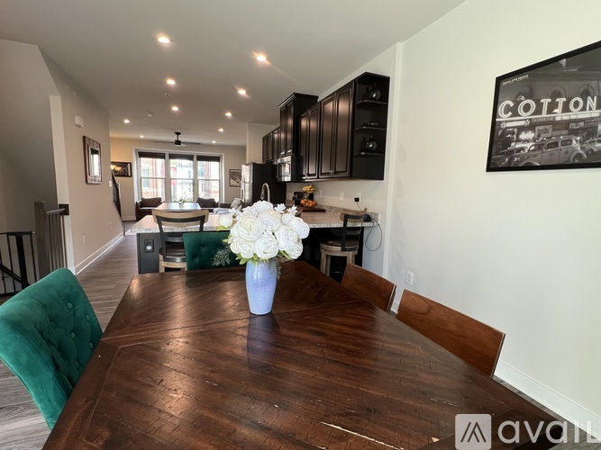 A dining room with a wooden table and a vase of white flowers.