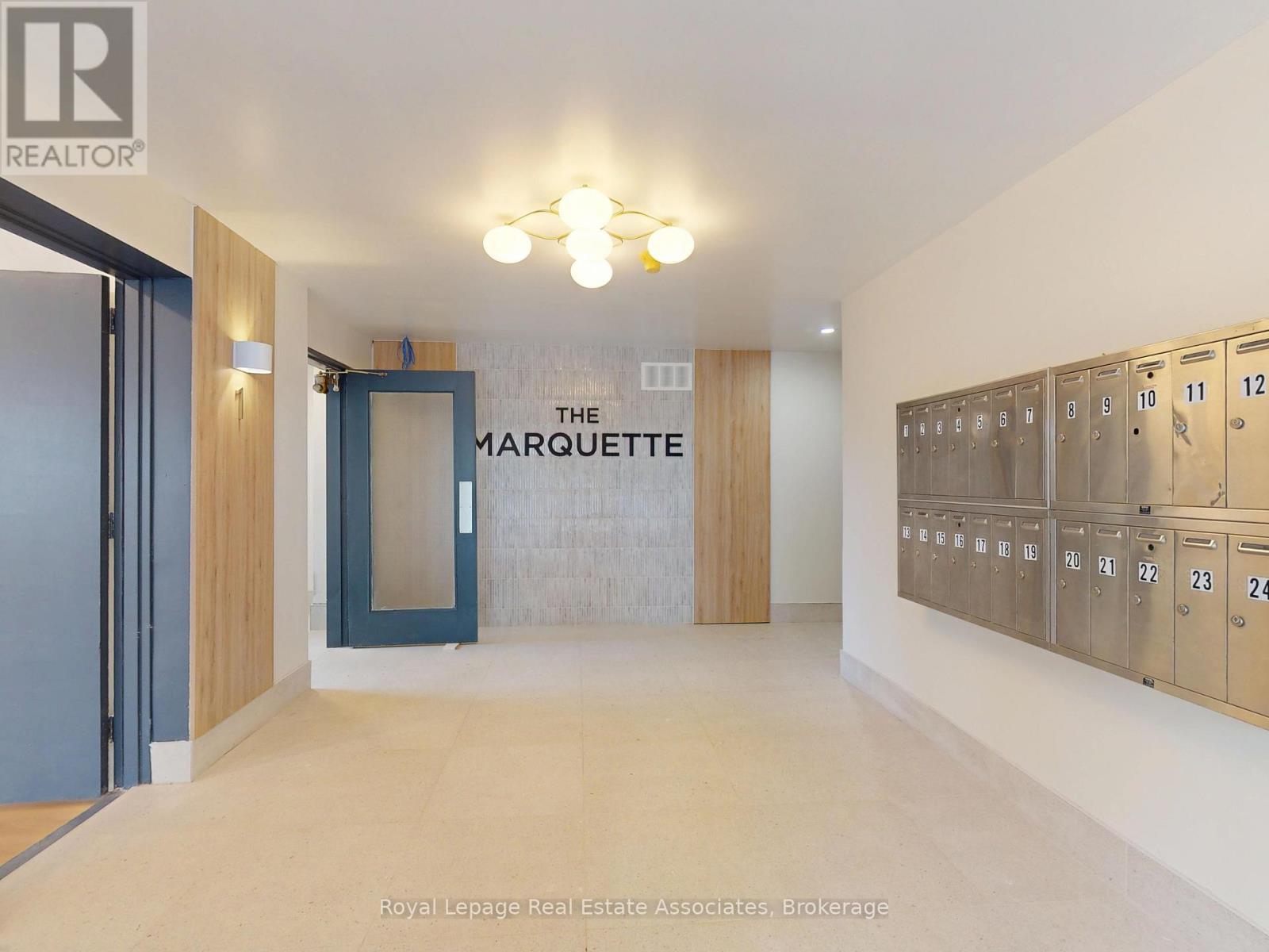 A hallway with a sign that says "The Marquette" and a row of lockers on the right side.