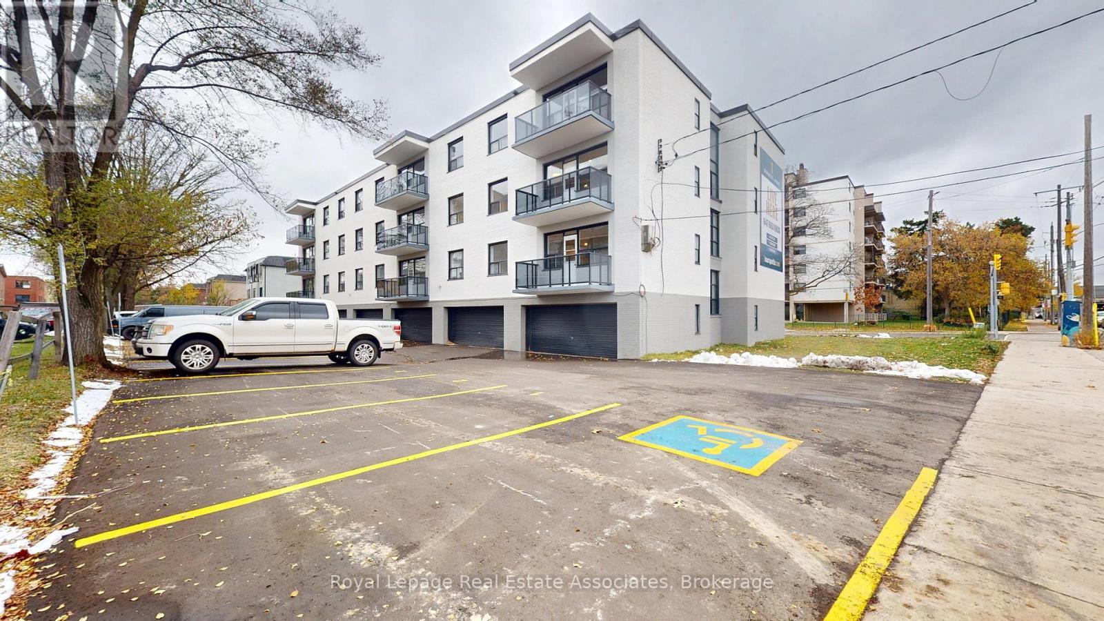 A white car is parked in a parking lot in front of a multi-story building.