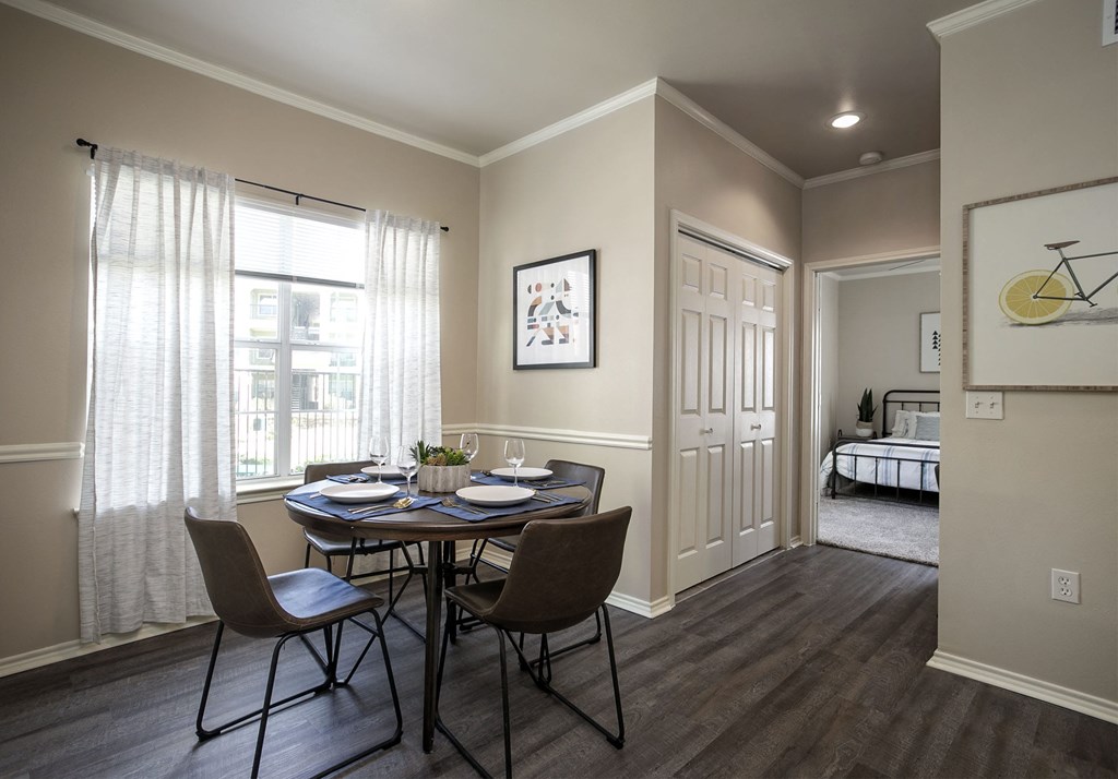 Apartments for Rent in Tyler, TX - Open-Concept Dining Room with Large Window, Wood Flooring, and Access to Bedroom.