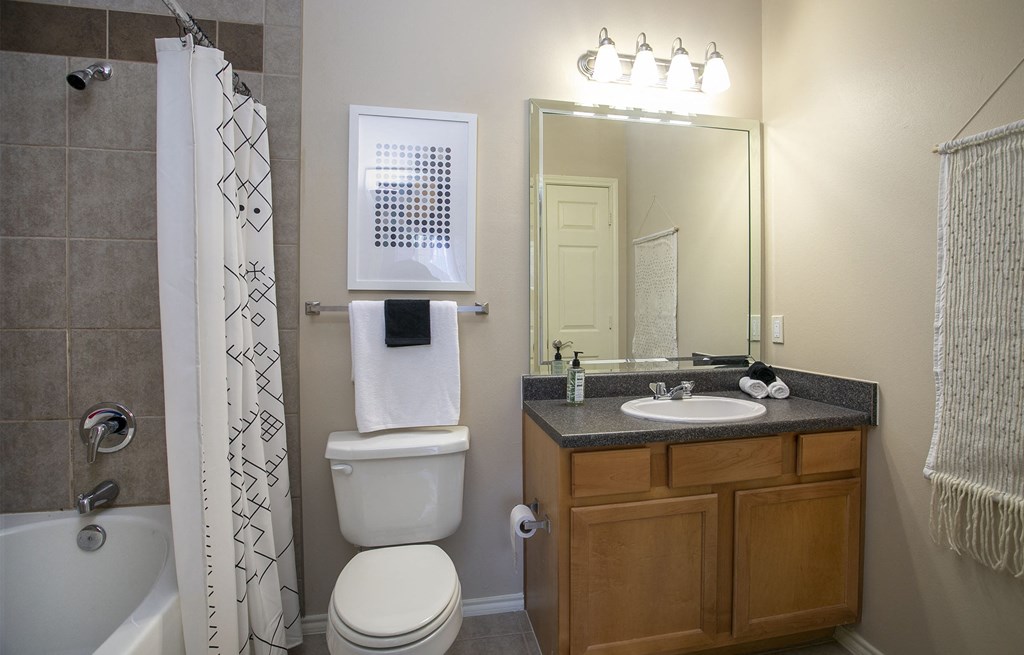 Apartments in Tyler, TX for Rent - Summerwood - Bathroom with Wood-Style Cabinets, a Toilet, and a Shower with a Bathtub