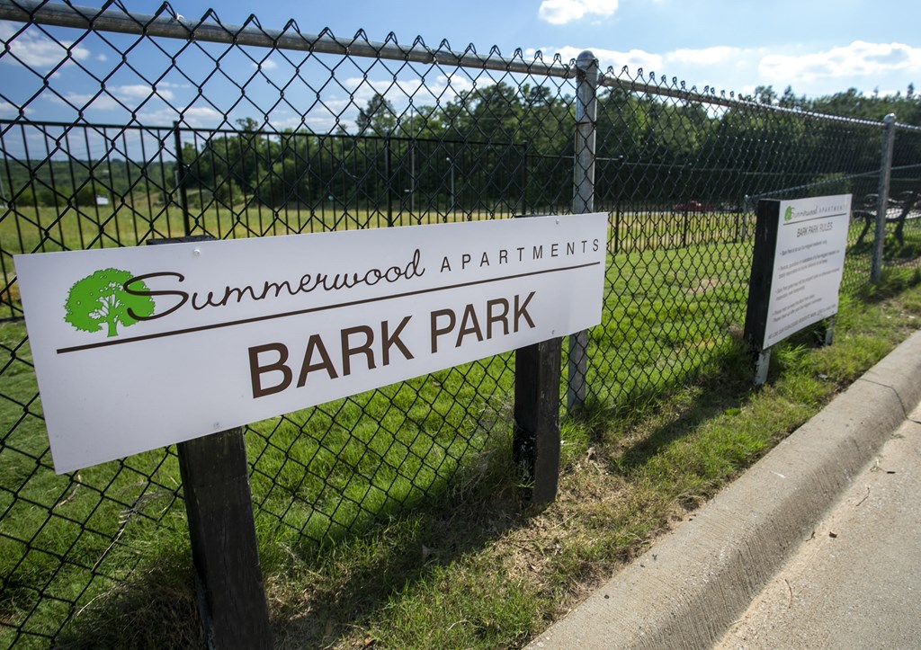 a sign for bark park in front of a fence