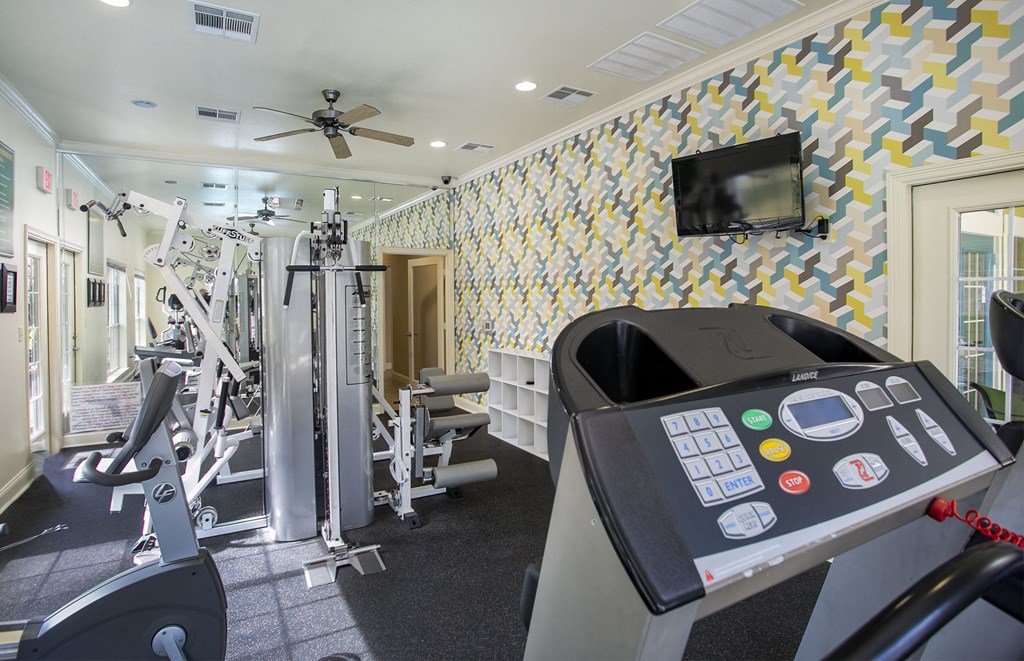 a gym with a treadmill and a tv