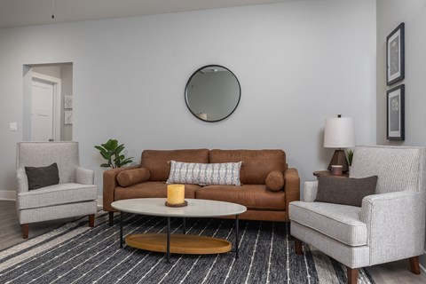 A living room with a brown couch, a grey armchair, and a white chair.