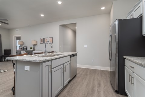 A kitchen with a black refrigerator and grey cabinets.