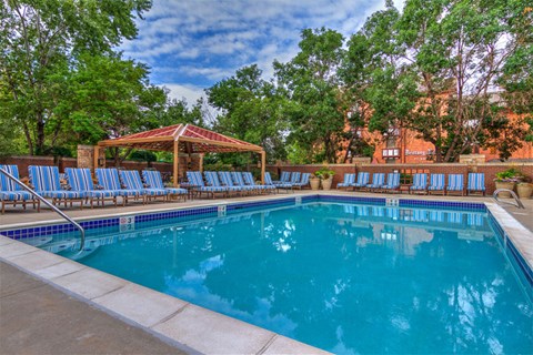 a swimming pool with blue chairs and a pavilion