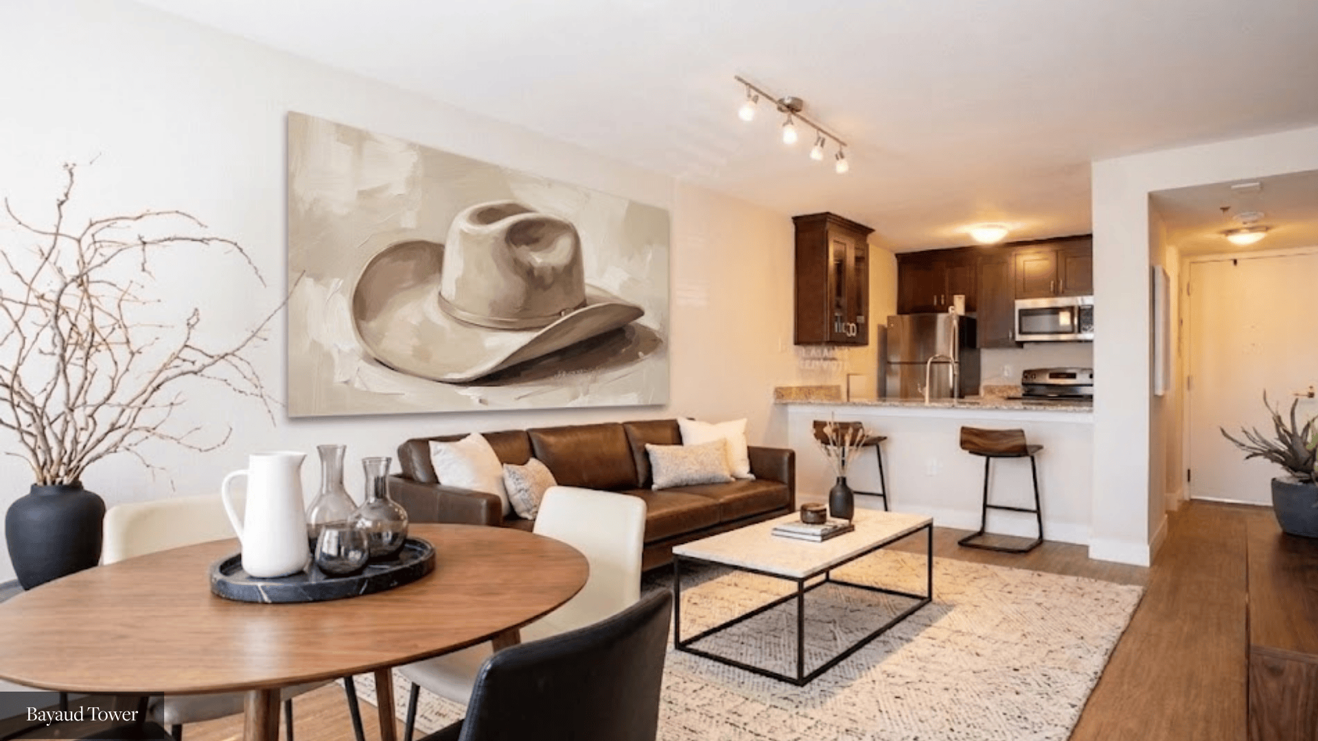 A cowboy hat is on a painting in a living room.