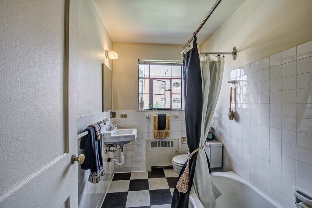 a bathroom with a checkered floor and a toilet and sink and a shower