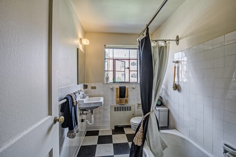 a bathroom with a checkered floor and a toilet and sink and a shower