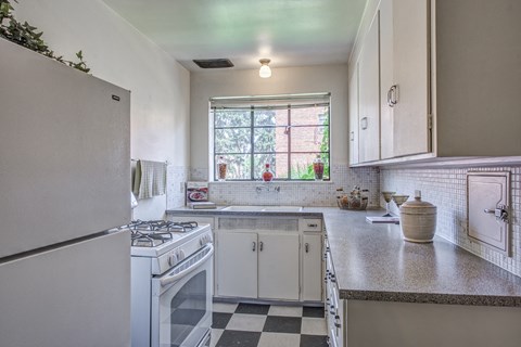 a kitchen with white appliances and a checkered floor
