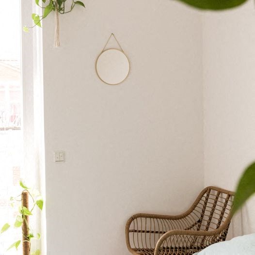 a bedroom with a wicker chair and a mirror on the wall