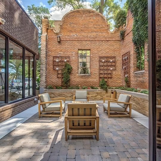 a patio with chairs and a table in front of a brick building