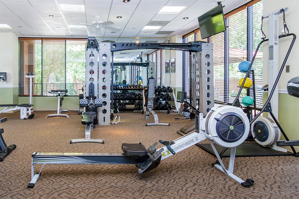 a gym with weights and other equipment in a room with windows