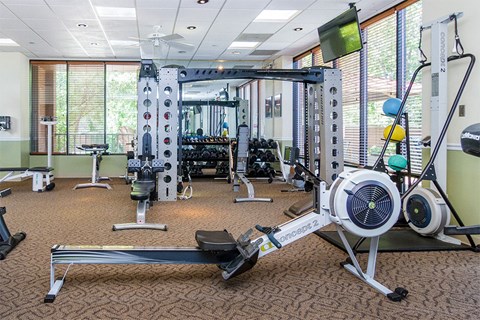 a gym with weights and other equipment in a room with windows