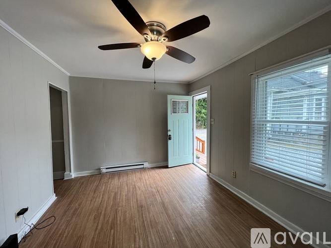 A room with a ceiling fan and wooden flooring.