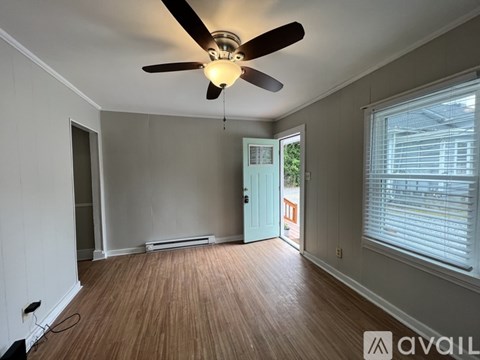 A room with a ceiling fan and wooden flooring.