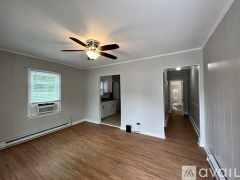 A room with a ceiling fan and wooden flooring.