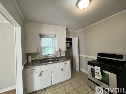 A kitchen with white cabinets and a black stove top oven.