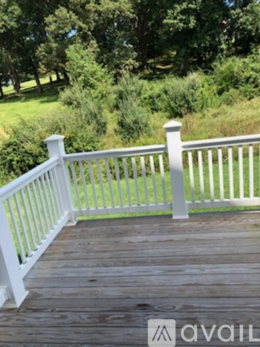 A wooden deck with white railings overlooks a green landscape.