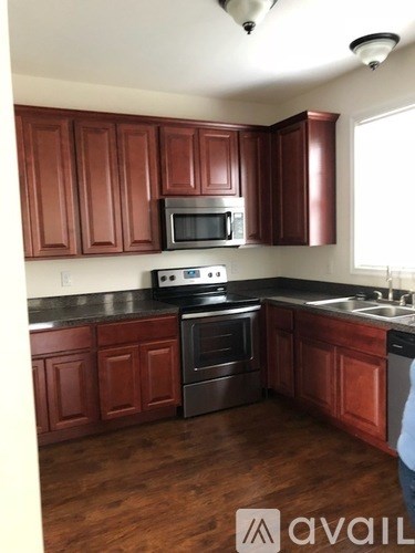 A kitchen with brown cabinets and a black stove top oven.