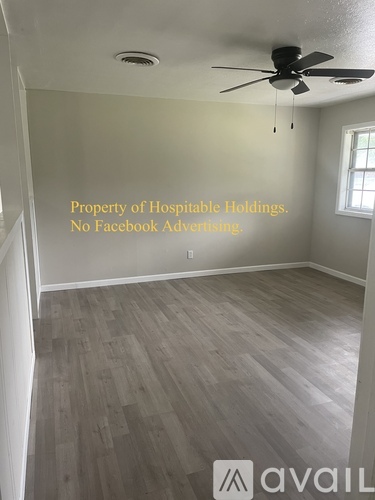 A room with a ceiling fan and a window with a sign that says "Property of Hospitable Holdings. No Facebook Advertising."