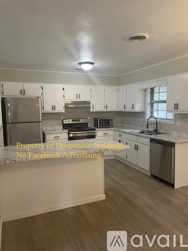 A kitchen with white cabinets and a wooden floor.