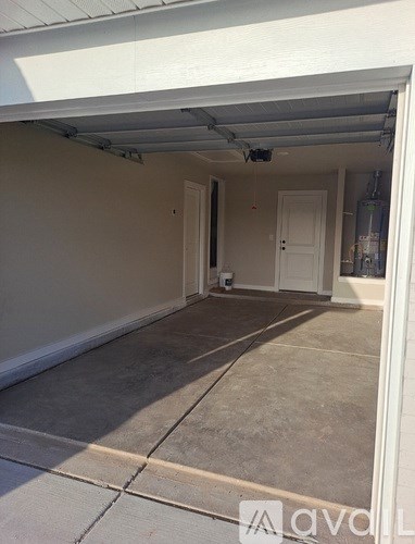 A white garage with a door open and a concrete floor.