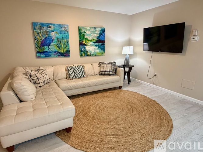 A living room with a couch, a lamp, and two paintings on the wall.