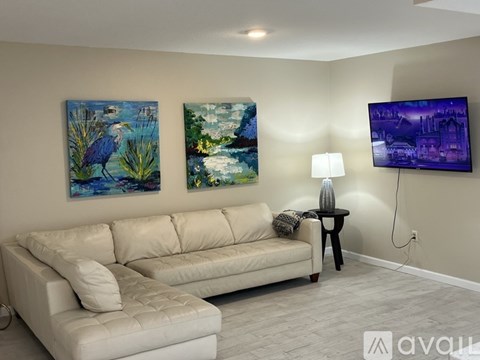 A living room with a couch, a lamp, and two paintings on the wall.