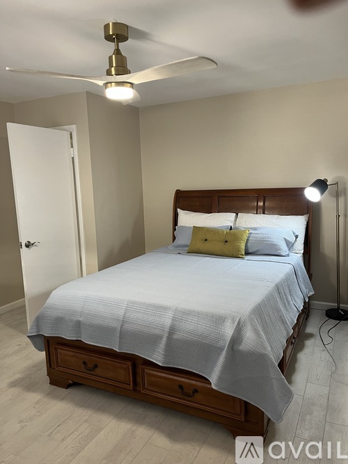 A bedroom with a bed, nightstand, and ceiling fan.