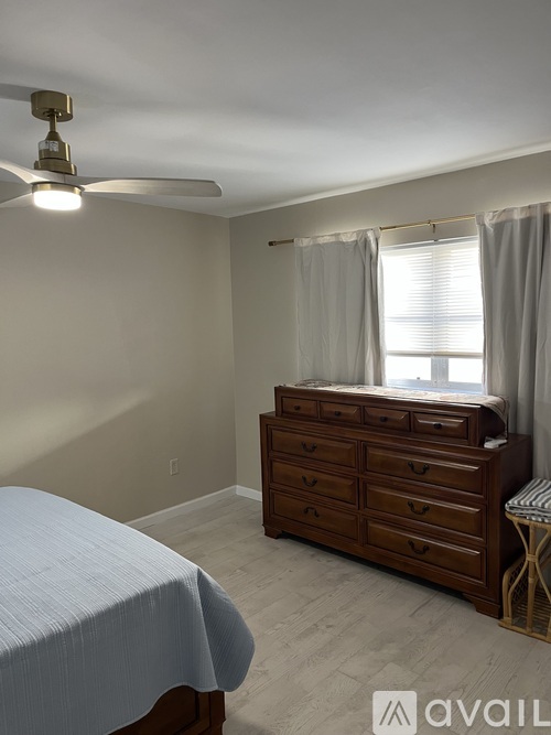 A bedroom with a bed, dresser, and window.