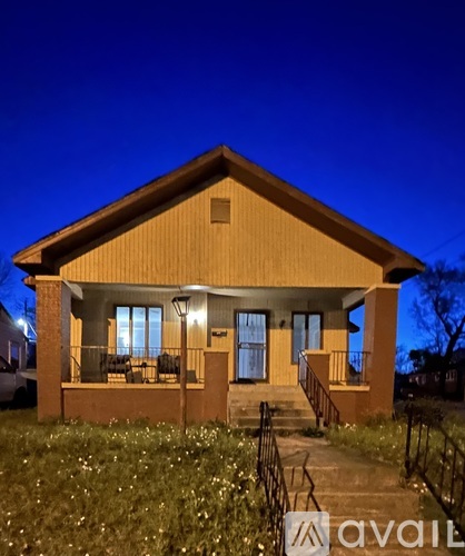 A house with a front porch and a lit lamp post.