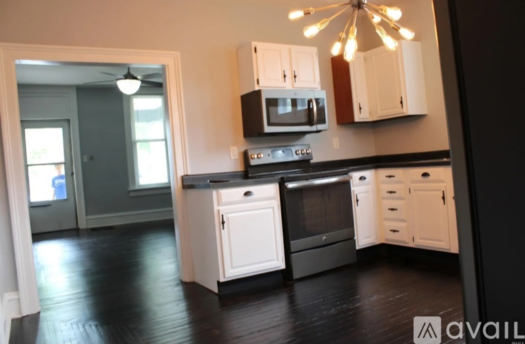 A kitchen with white cabinets and black countertops.