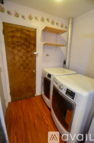 A small room with a wood floor and a wall with a tile patterned door and a wall shelf.