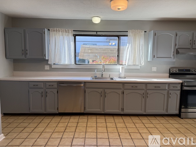 A kitchen with grey cabinets and a tiled floor.