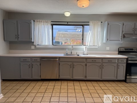 A kitchen with grey cabinets and a tiled floor.