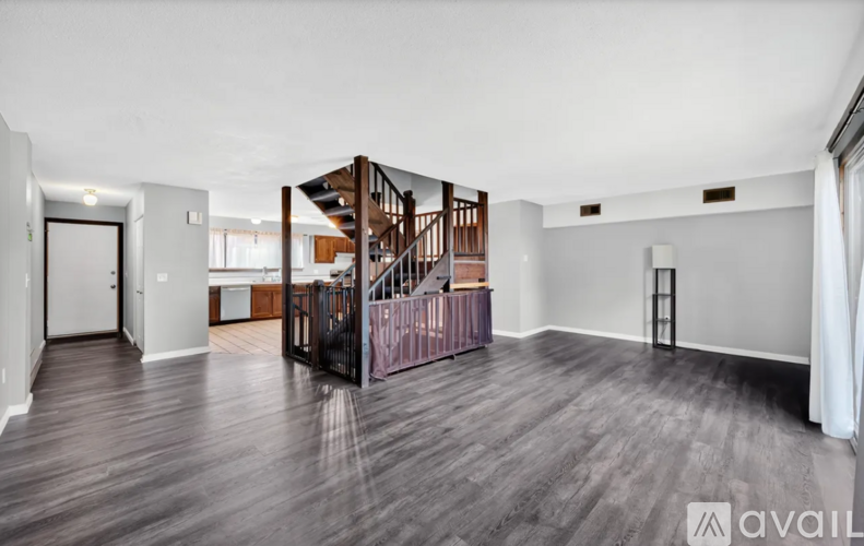 A spacious room with wooden floors and a staircase.
