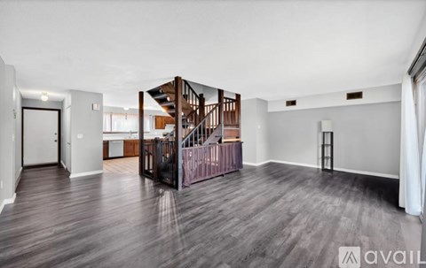 A spacious room with wooden floors and a staircase.